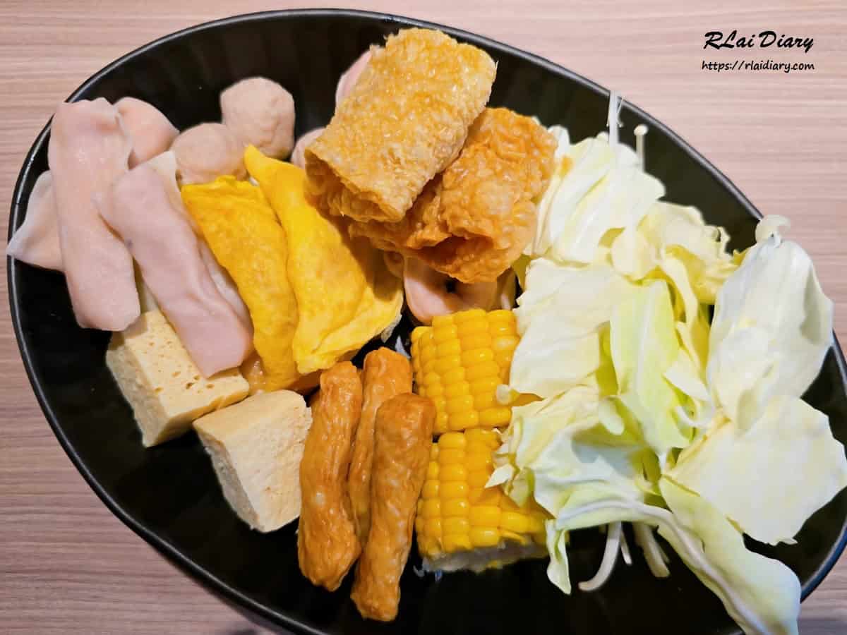 從自助吧夾取的豐盛菜盤，包含高麗菜、玉米與火鍋料