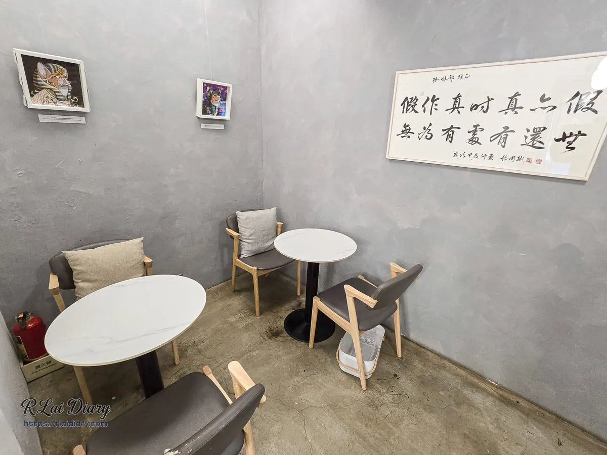 店內角落的雙人座位區，牆面掛有插畫與書法字畫，增添藝術氣息