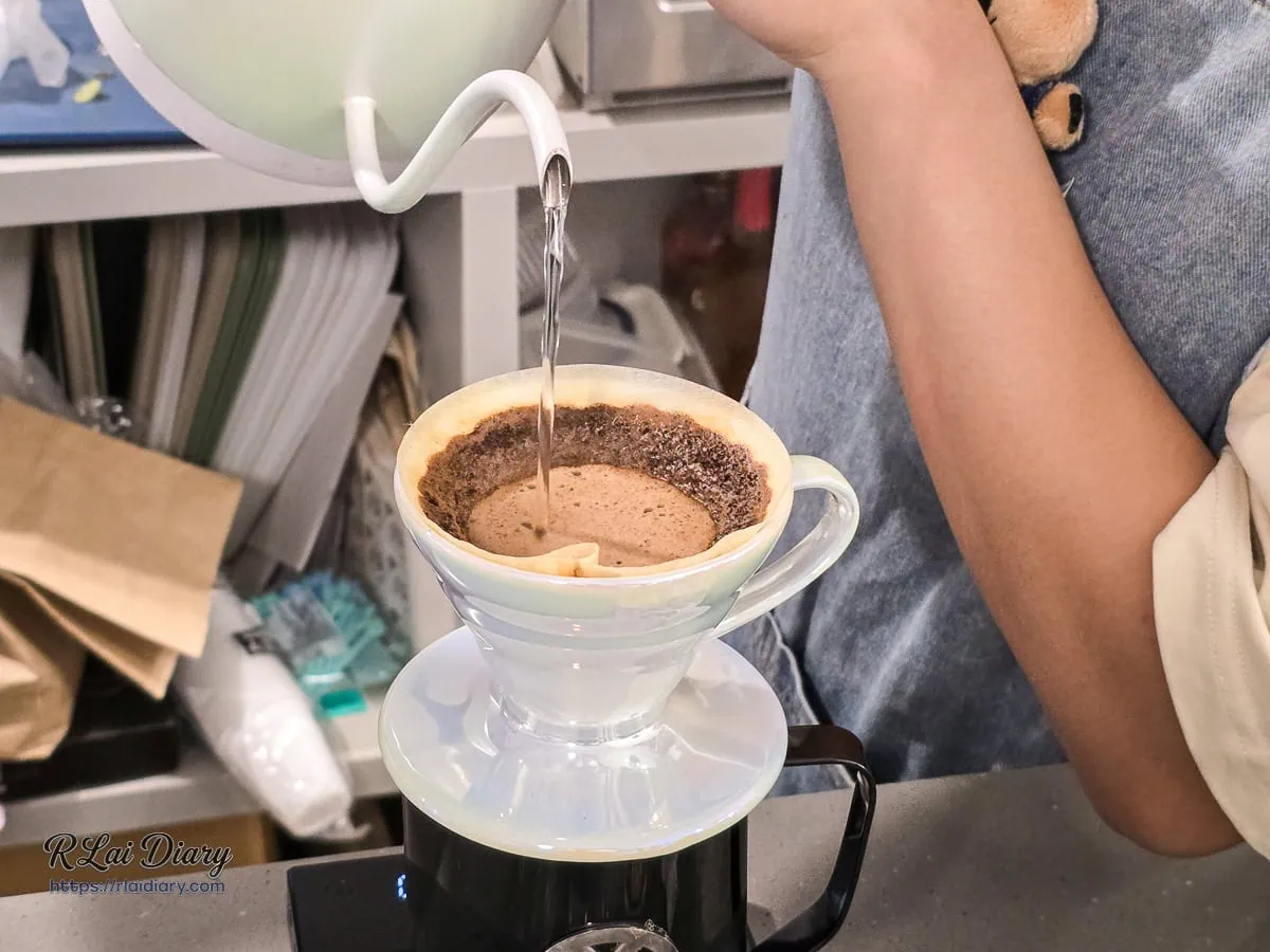 咖啡師正在進行手沖咖啡注水，展現專業的咖啡製作過程
