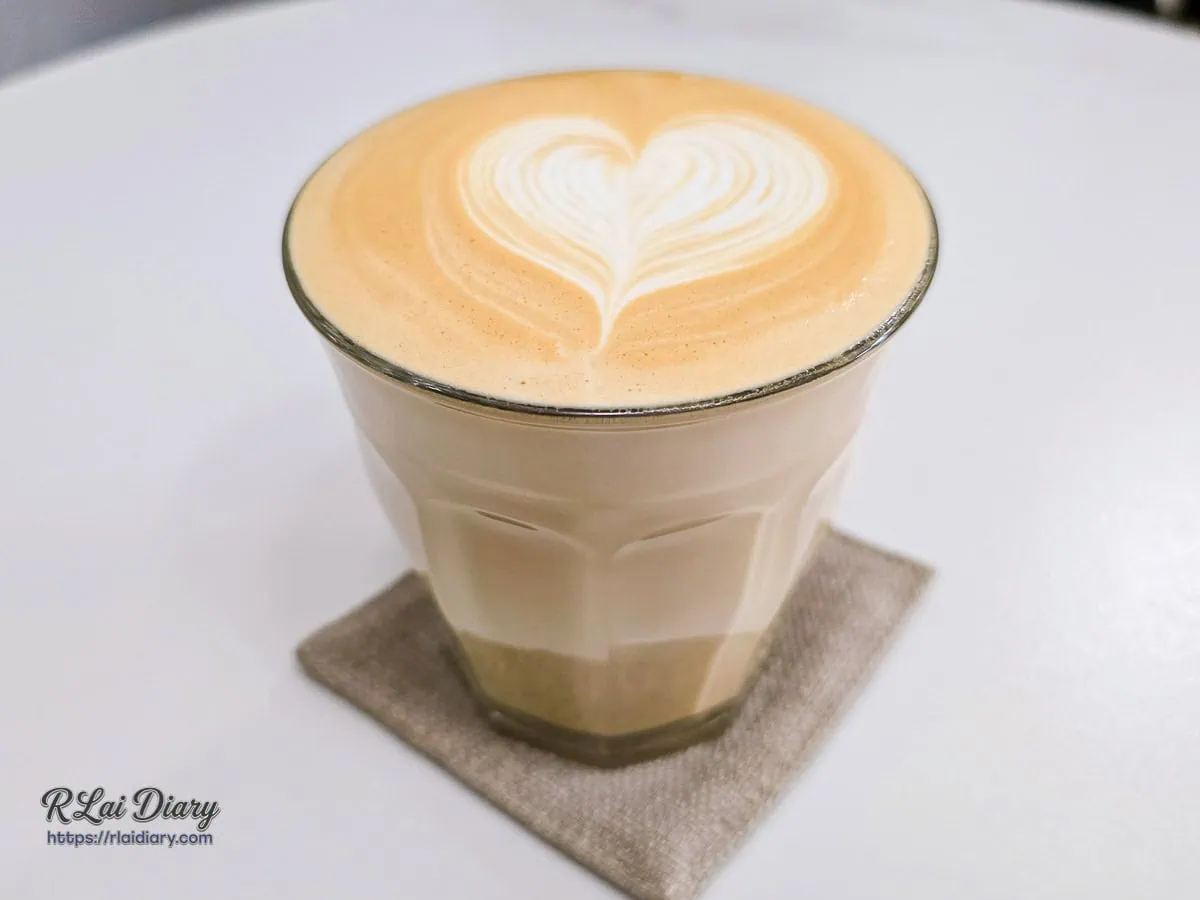 使用玻璃杯盛裝的熱拿鐵，從側面可見奶泡與咖啡的融合層次