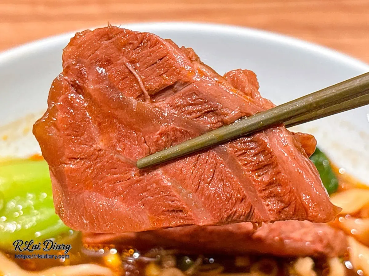 筷子夾起帶有細緻紋理與滷汁光澤的紅燒牛肉塊