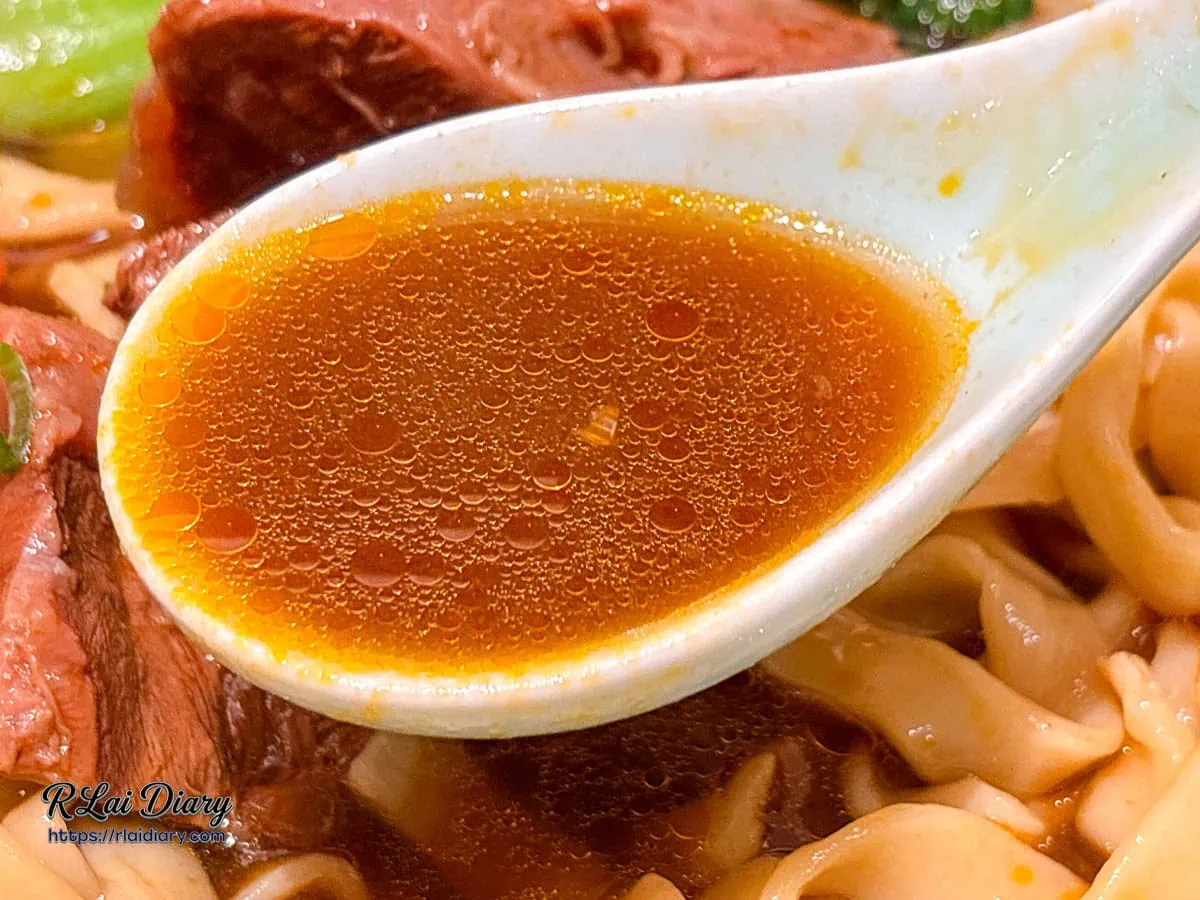 湯匙舀起精燉紅燒湯頭，清澈透亮且帶有濃郁牛油香氣