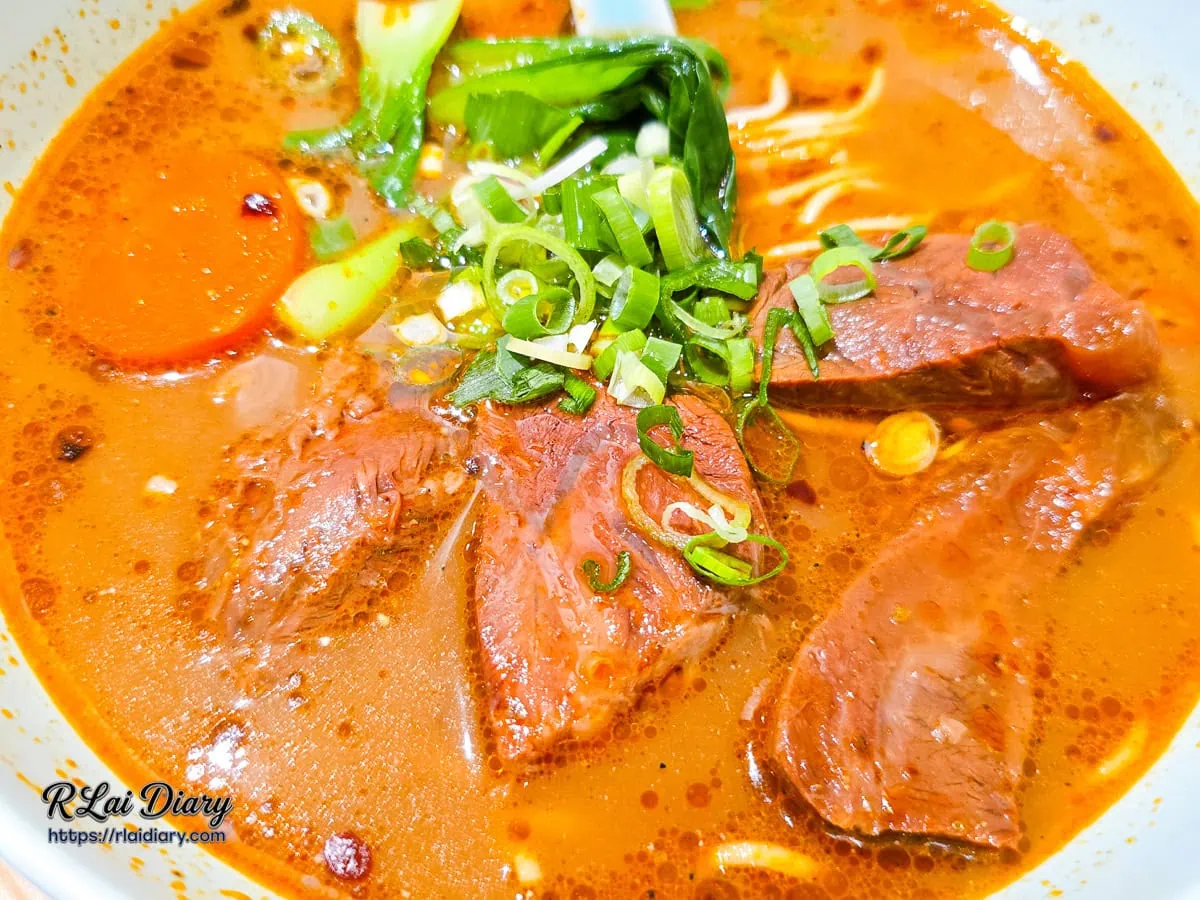 川香麻奶牛肉麵近拍，清晰可見軟嫩牛腱肉、蔥花與紅蘿蔔