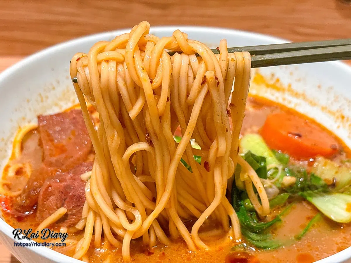 筷子夾起吸附滿滿川香麻奶湯汁的細麵條特寫