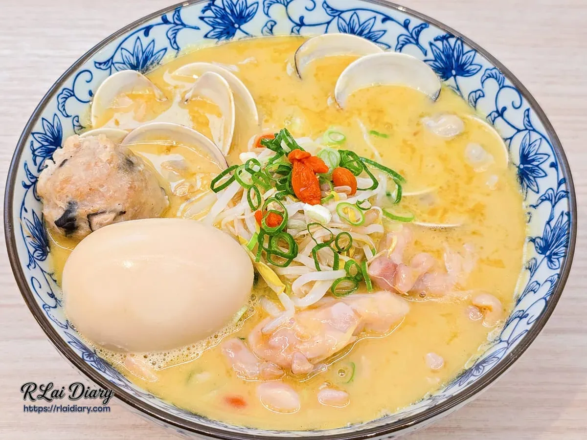 蛤蜊雞腿濃湯麵，碗中滿鋪蛤蜊、溏心蛋、貢丸與鮮嫩雞肉