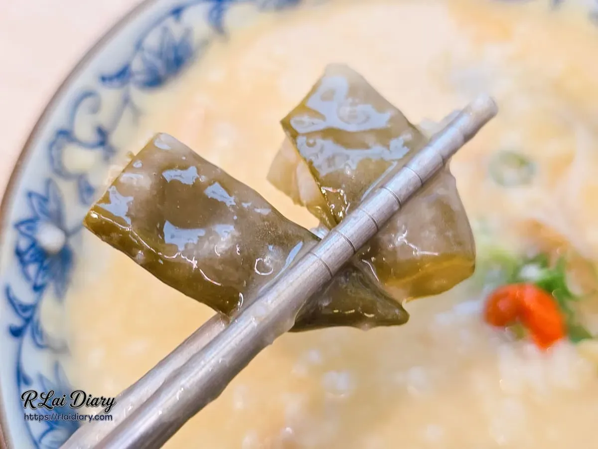 夾起粥裡的剝皮辣椒特寫，風味甘甜微辣