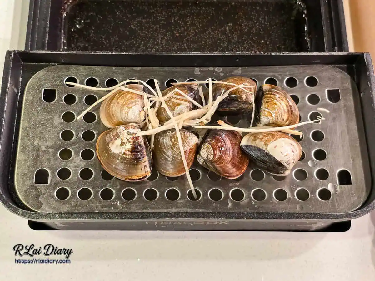將蛤蠣蒸盤架設於火鍋湯底上方，利用水蒸氣蒸熟海鮮