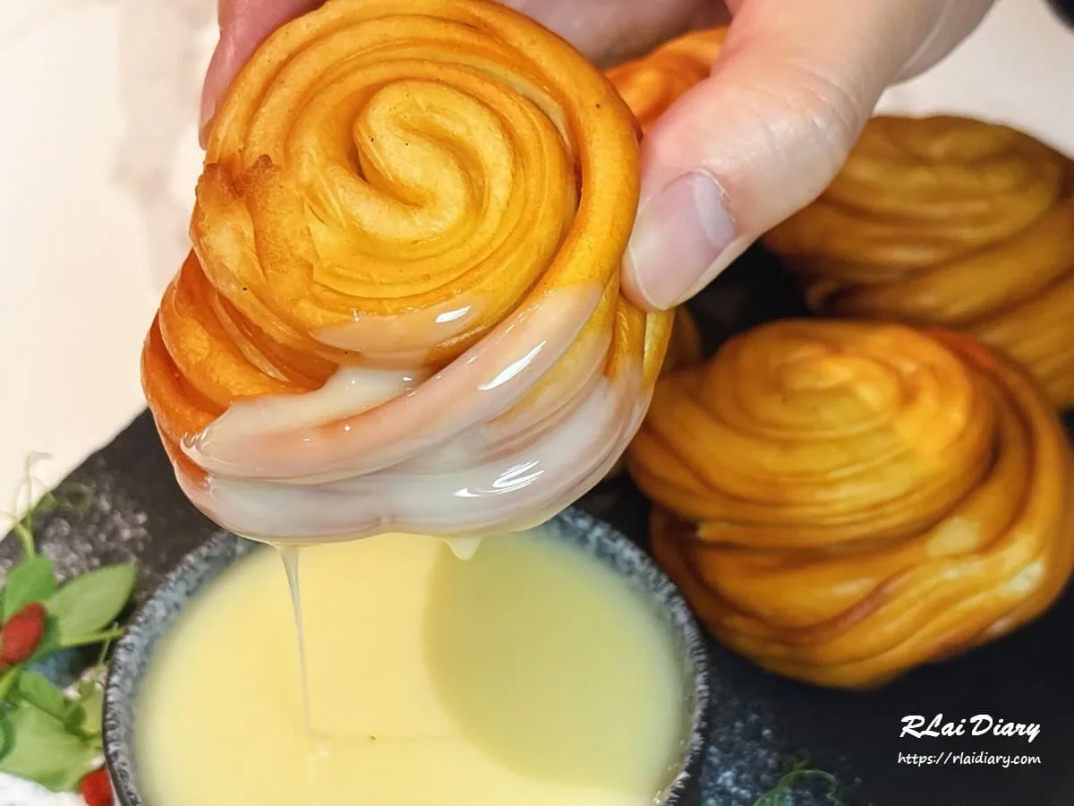 螺絲捲沾煉乳特寫，外酥內軟的麵包體裹上香甜煉乳的療癒畫面