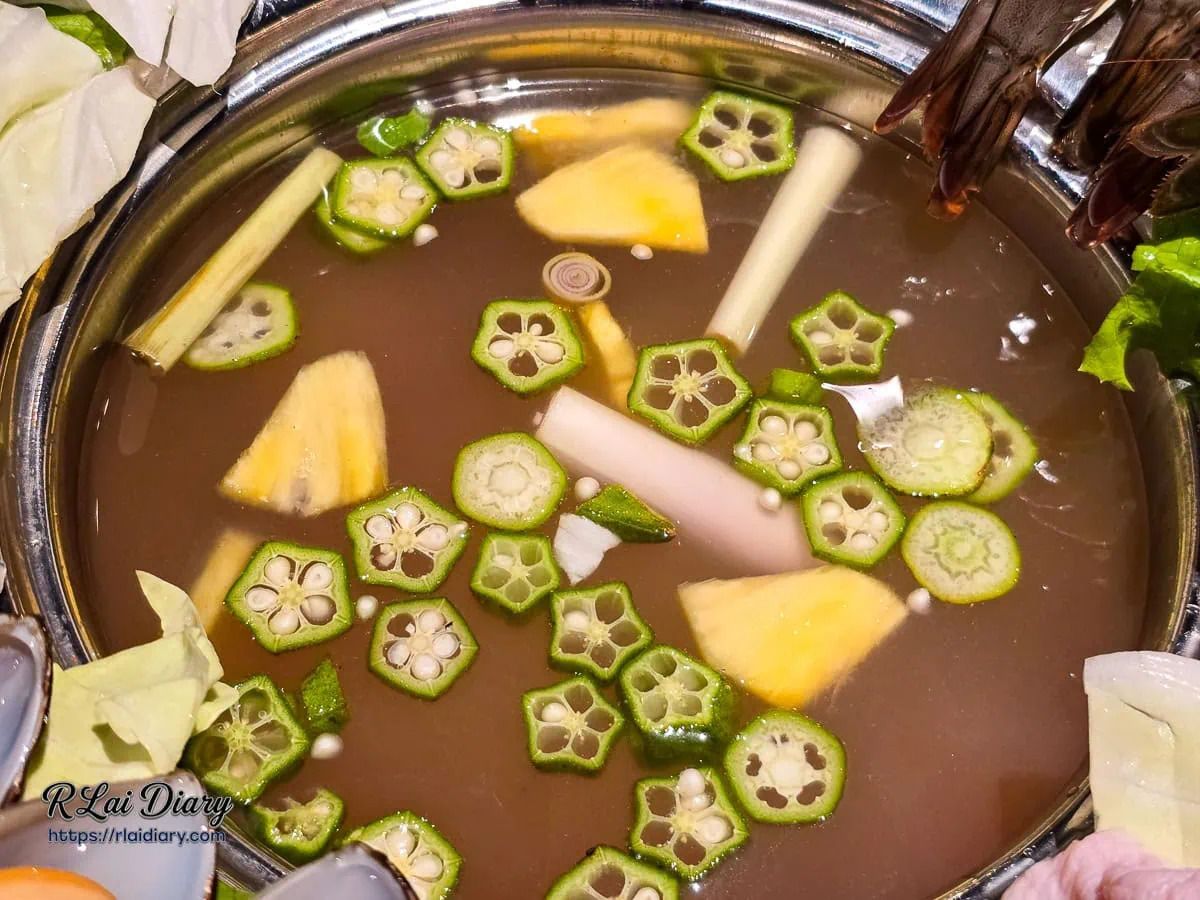 海陸推推鍋湯底特寫，清澈湯頭中漂浮著秋葵與鳳梨片，風味酸甜開胃