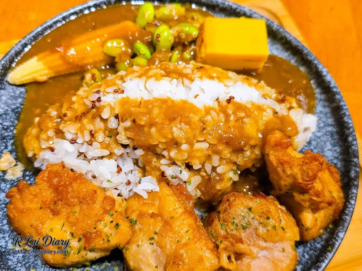 將濃郁咖哩醬淋在藜麥飯與唐揚雞上的美味瞬間