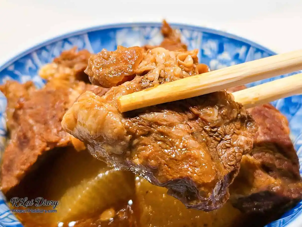 大力黑金滷肉飯爆汁大塊牛腩，筷子夾起帶有迷人油花與膠質筋膜的軟嫩牛肉特寫。