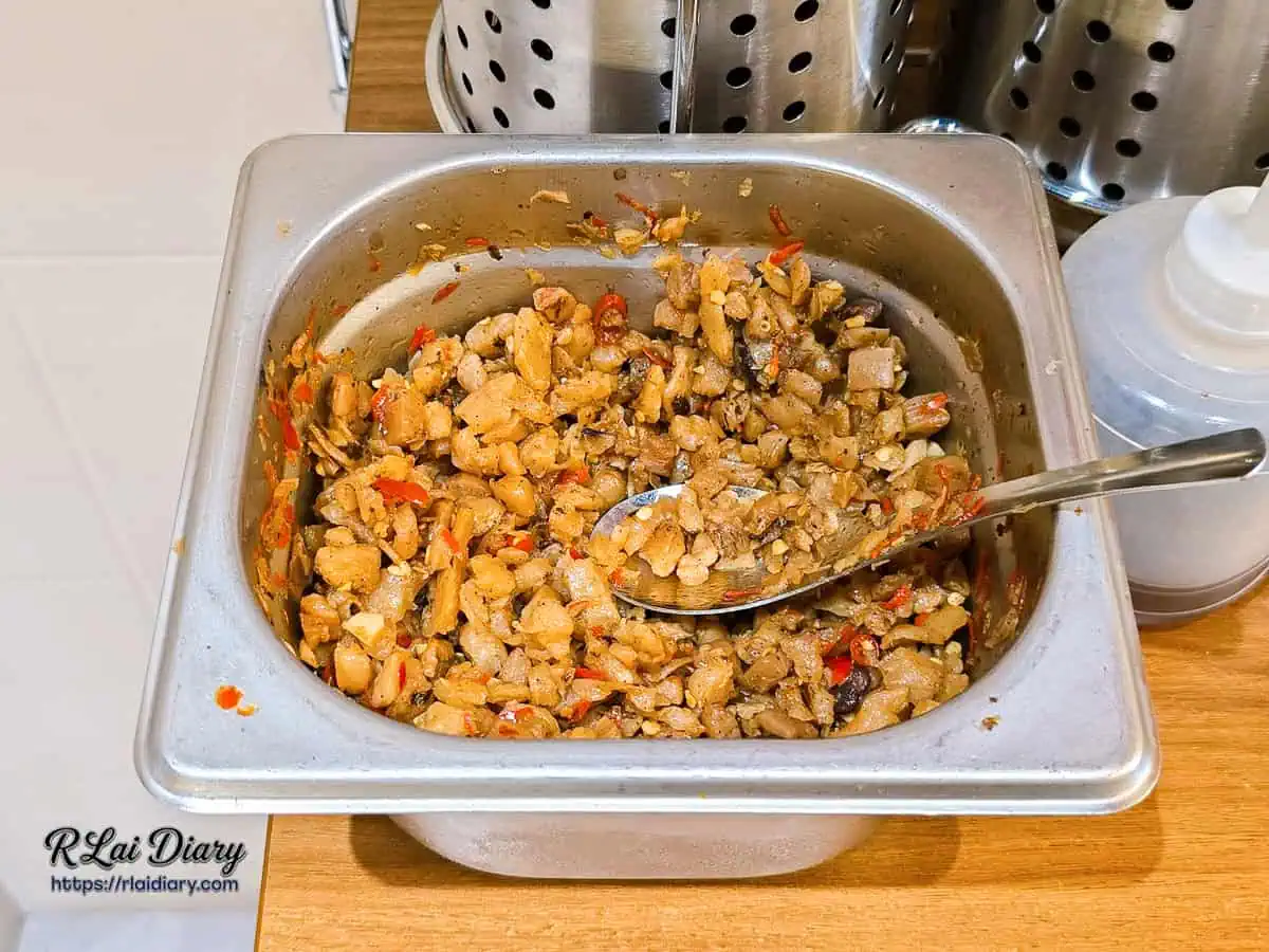 大力黑金滷肉飯自助區不鏽鋼盆，裝滿無限量供應的脆口辣炒蘿蔔乾搭配豆豉。