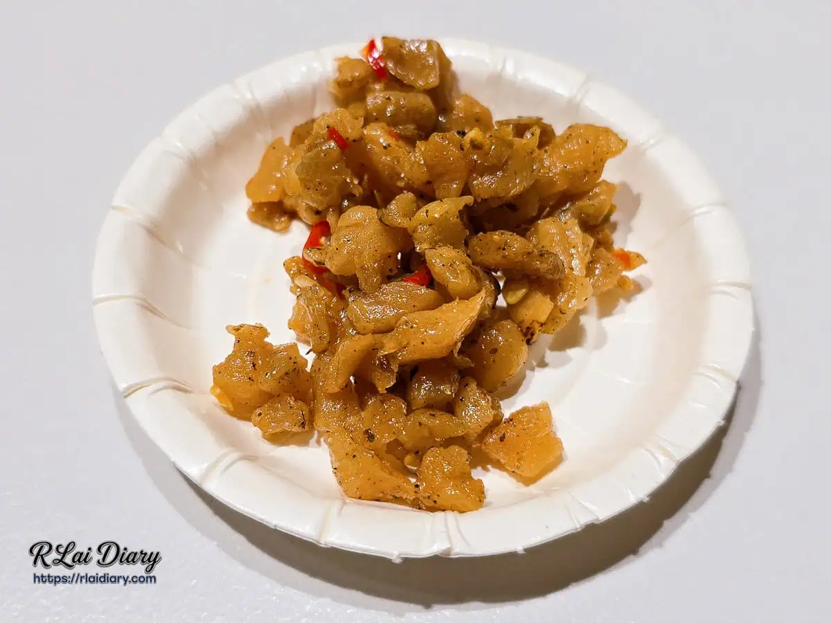 大力黑金滷肉飯秘製辣炒菜脯，裝在白色紙盤上呈現琥珀色澤與鮮紅辣椒碎的微距特寫。
