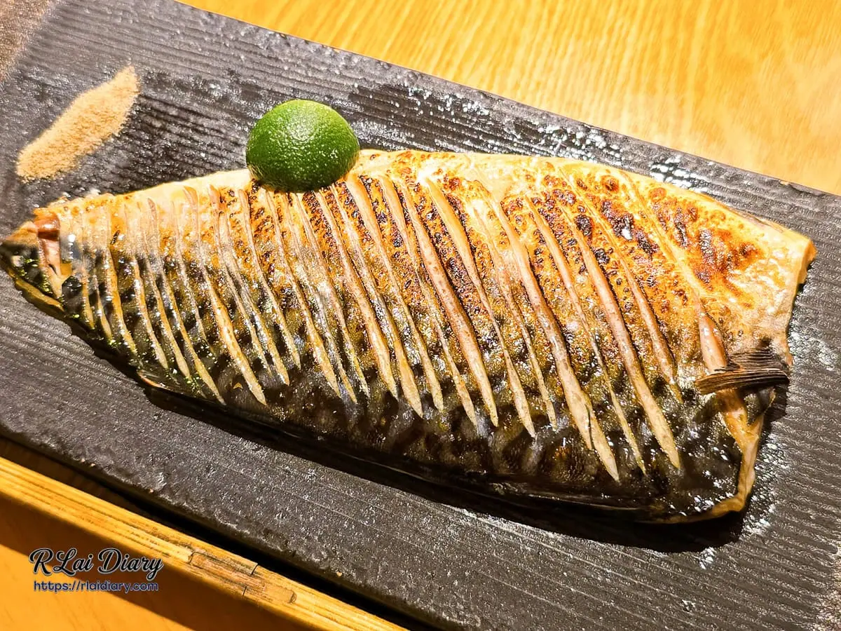 台中丹丘たんきう現烤薄鹽烤鯖魚特寫，金黃酥脆魚皮與豐盈油脂光澤搭配翠綠金桔