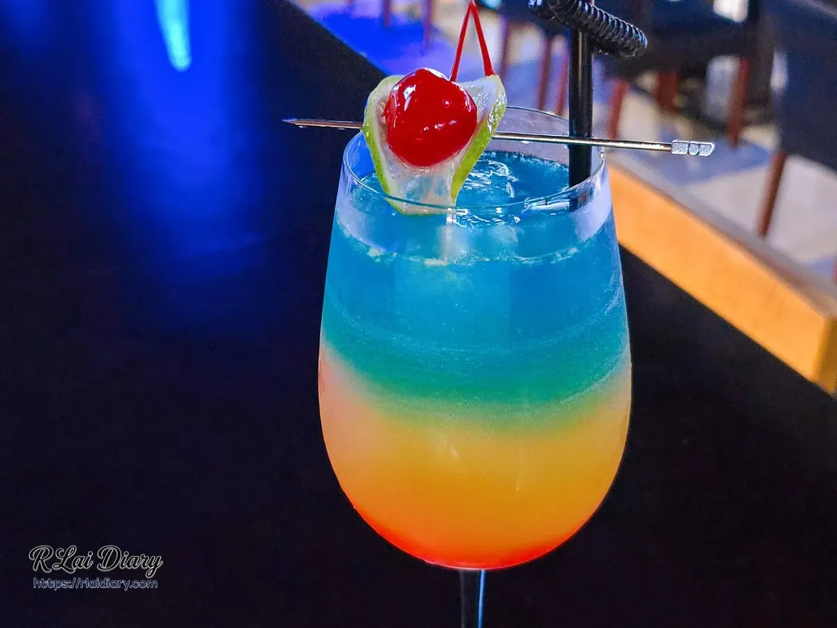 G CLUB TAIPEI 招牌調酒「環遊世界」近照，玻璃杯中呈現艷紅到湛藍的絕美熱帶漸層色彩