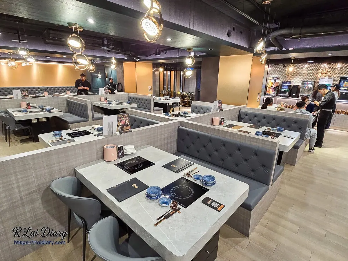 新肉多多台北忠孝店寬敞用餐環境，暖色環形金屬吊燈與香檳金牆面點綴，遠處可見自助吧檯區