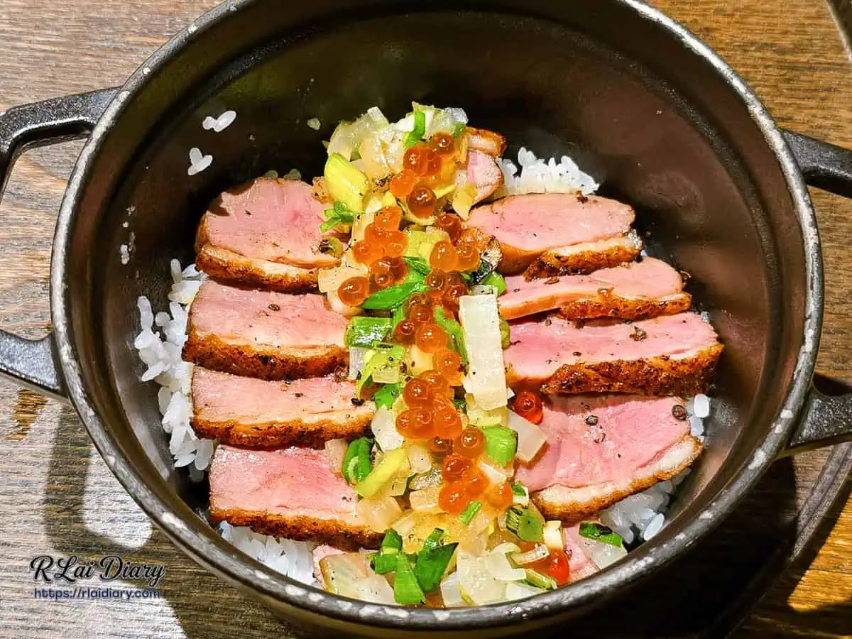 鑄鐵鍋內的櫻桃鴨胸蓋飯，搭配蔥花與鮭魚卵