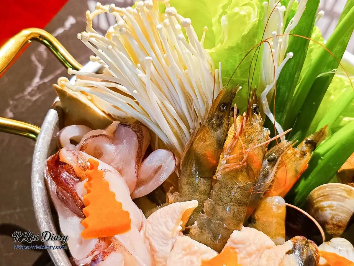 麓島居酒聚場海陸寄ㄝ鍋特寫，滿出的鮮蝦、透抽與金針菇蔬菜盤