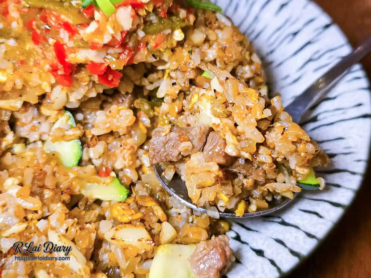 湯匙舀起剁椒奶油牛小排炒飯，特寫牛小排肉丁、櫛瓜與油亮米飯