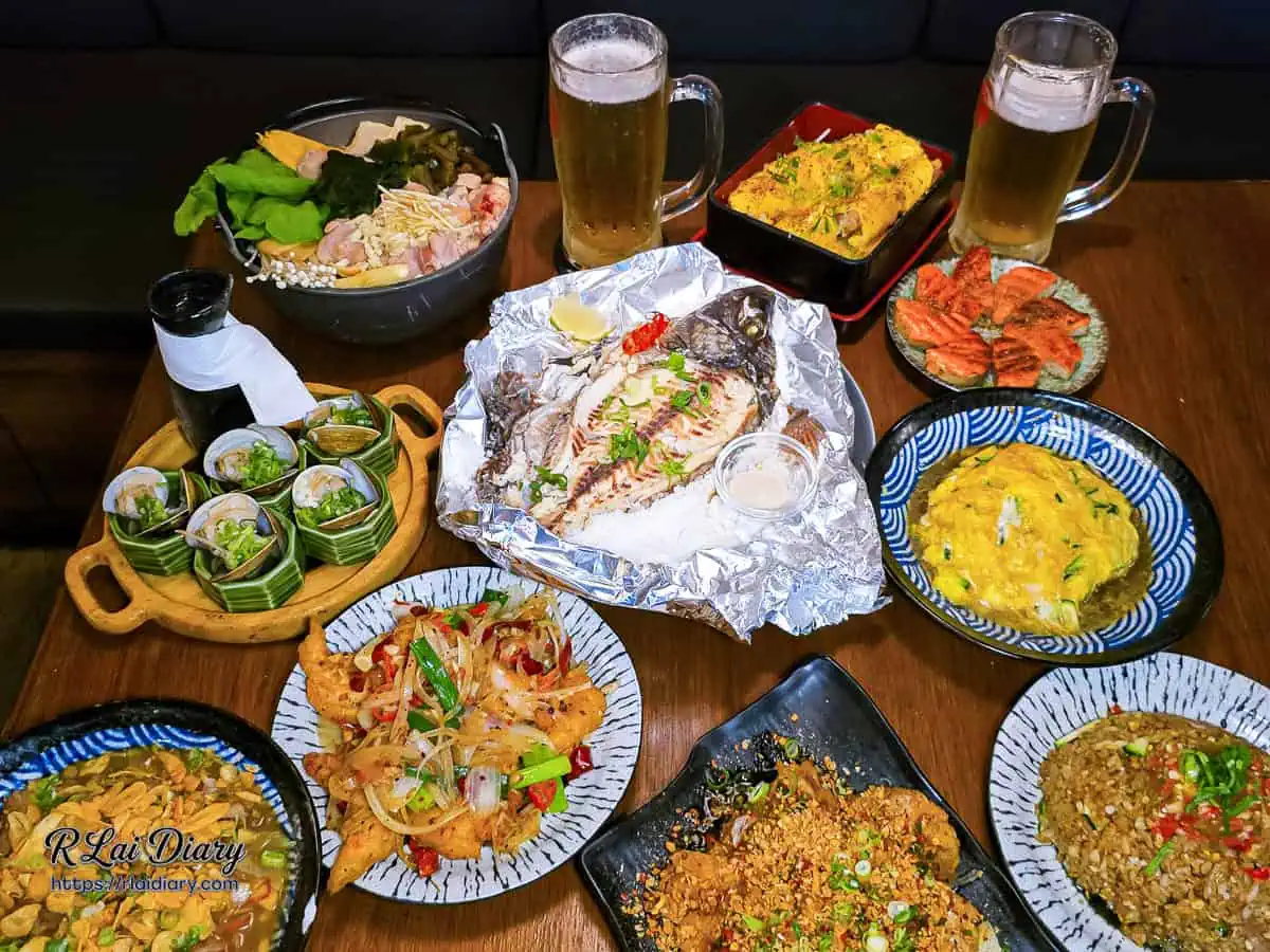 宇貳居酒屋滿漢全席餐點合照,包含剝皮辣椒雞鍋、鹽焗魚、各類熱炒與Orion生啤酒
