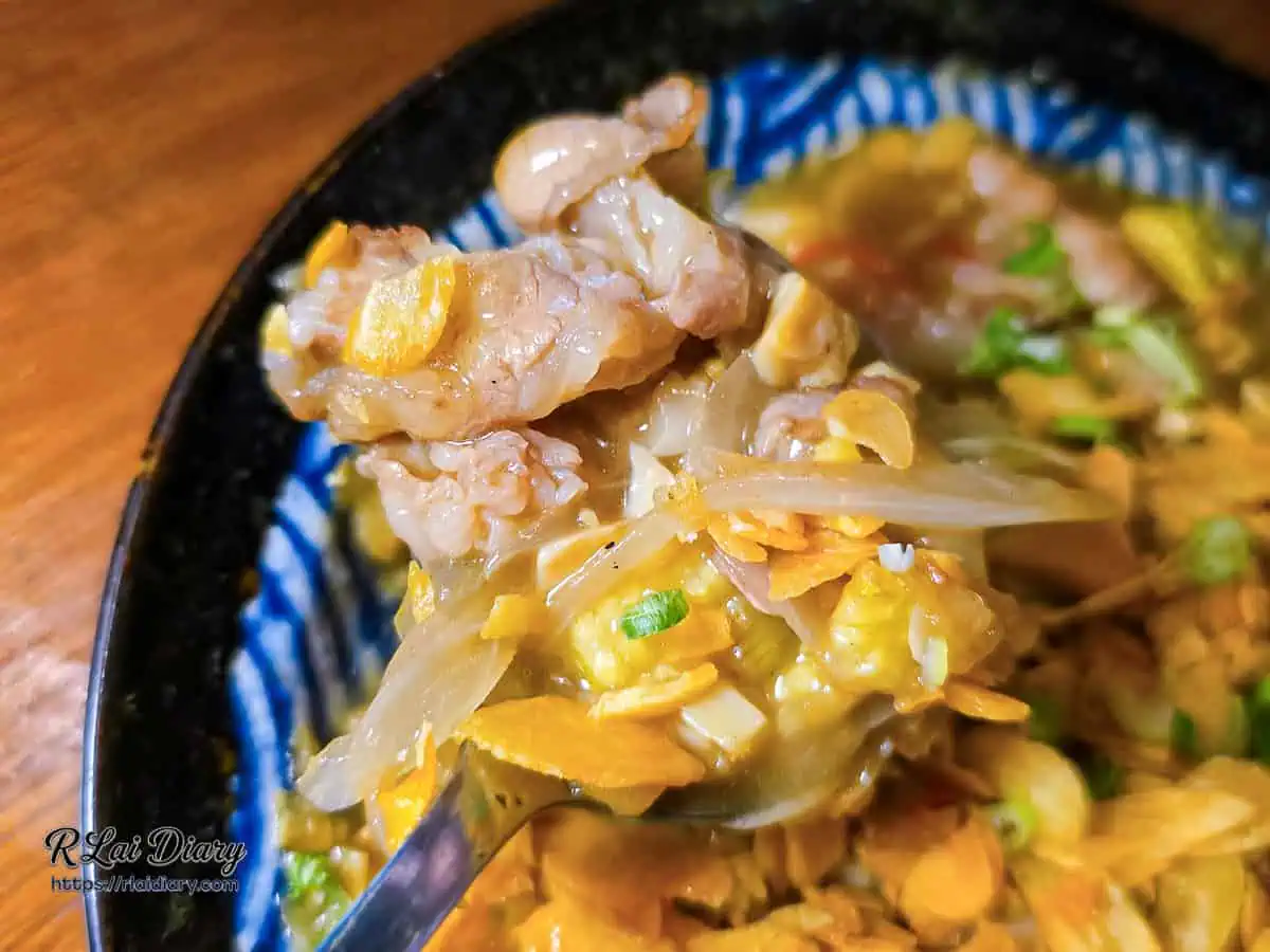 湯匙舀起奶油蒜香肥牛，顯示吸飽奶香醬汁的牛肉、洋蔥與玉米筍
