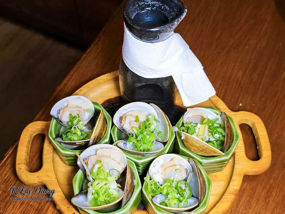 宇貳居酒屋酒蒸蛤蜊，精緻綠色六角杯盛裝蛤蜊圍繞清酒壺的擺盤