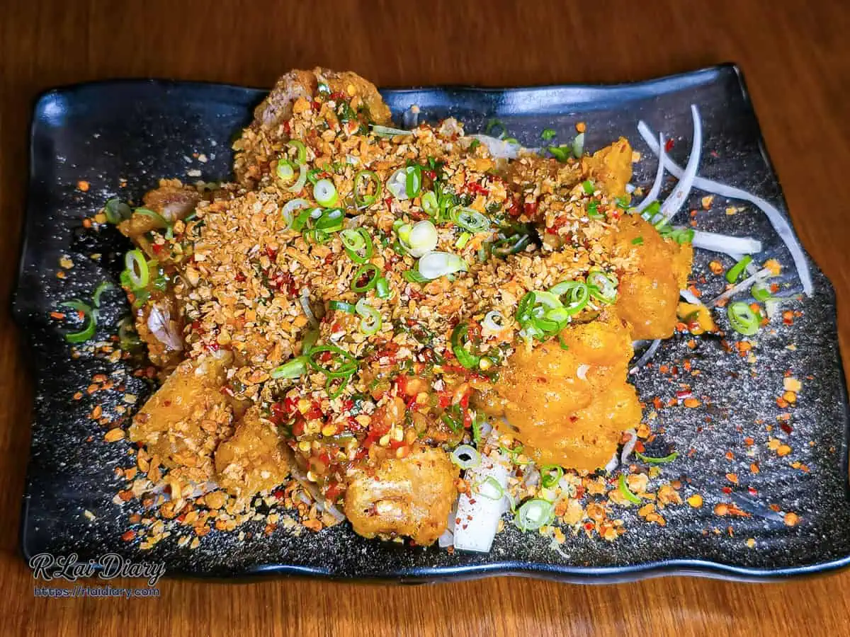 宇貳居酒屋招牌菜宇貳椒麻雞，金黃炸雞腿肉搭配大量蒜酥與蔥花辣椒