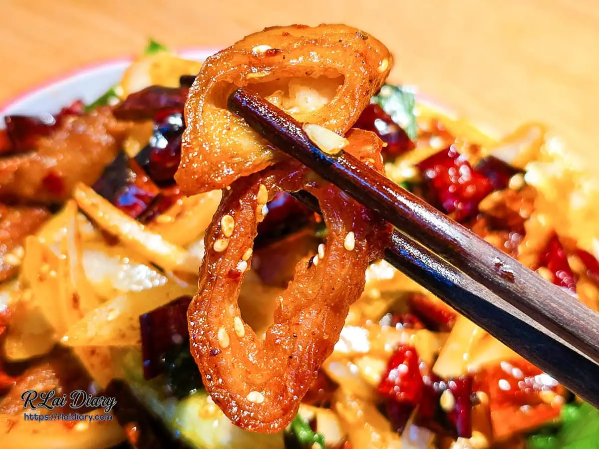 筷子夾起正太酸菜魚乾煸肥腸特寫展現酥脆金黃外皮與白芝麻