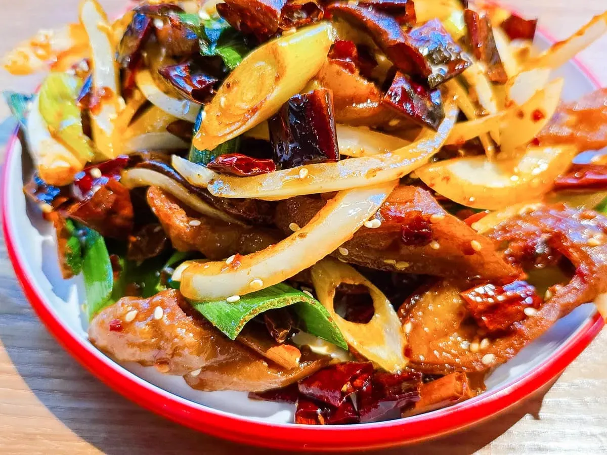 正太酸菜魚乾煸肥腸側面特寫呈現焦糖色澤與豐富配料層次