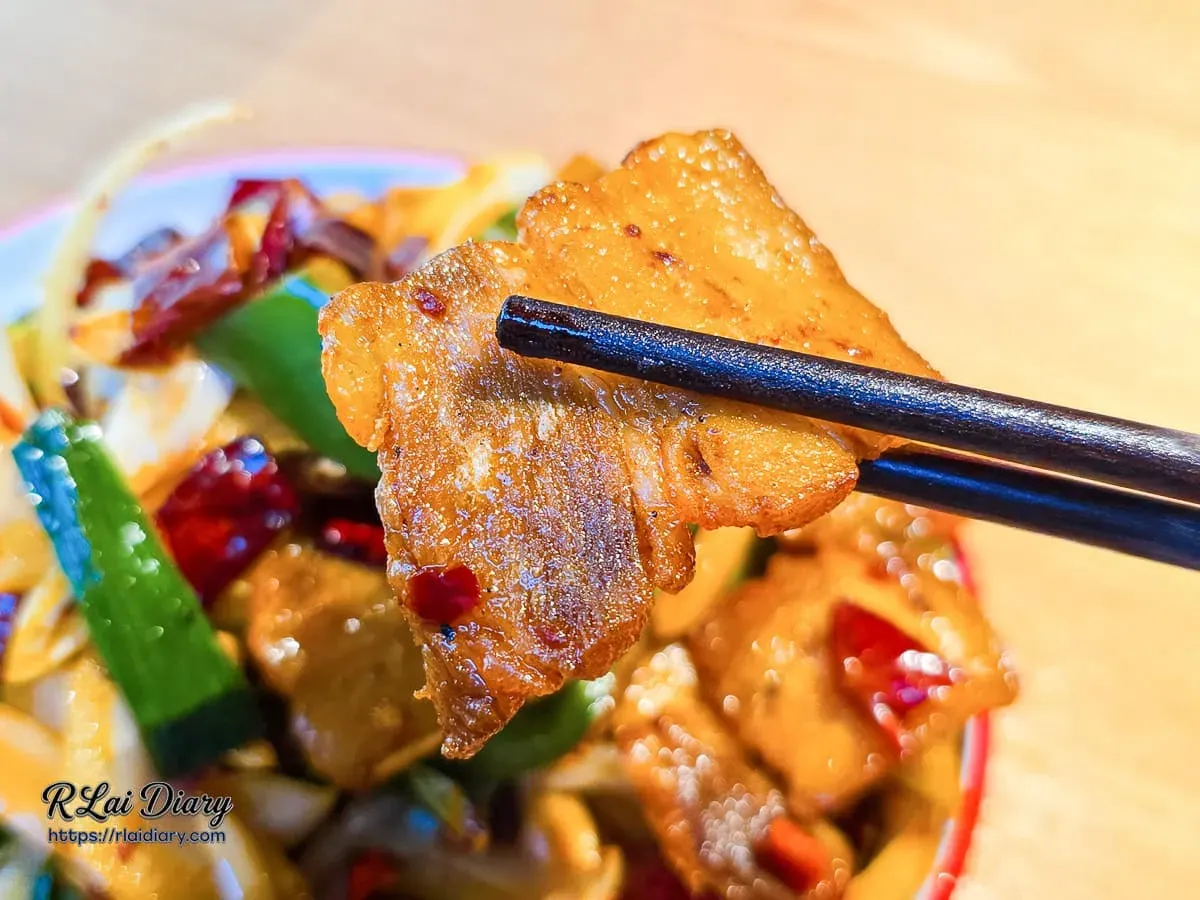 筷子夾起正太酸菜魚回鍋肉片特寫展現肥瘦相間與油亮醬色