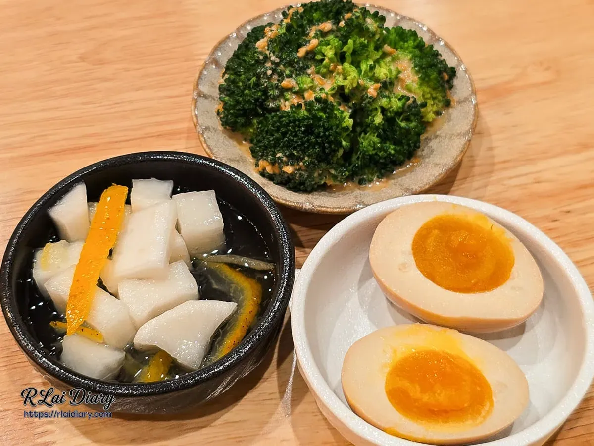 簡餐附屬配菜：柚香醃蘿蔔、胡麻花椰菜與橙紅潤澤的半熟溏心蛋