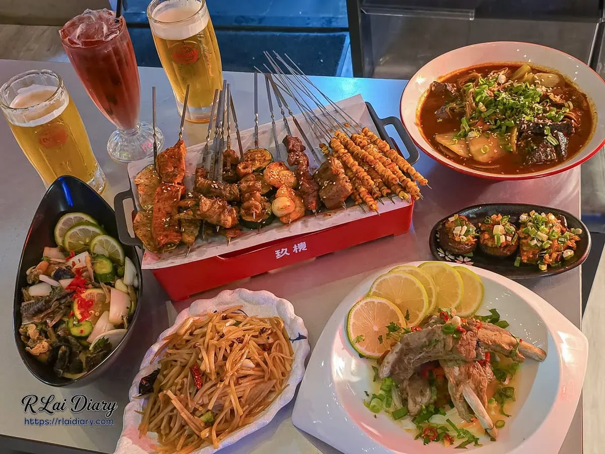 台中西區玖樓重慶麻辣烤串滿桌豐盛餐點,包含招牌現烤串燒、麻辣燙、烈焰排骨、金絲土豆與沁涼生啤酒