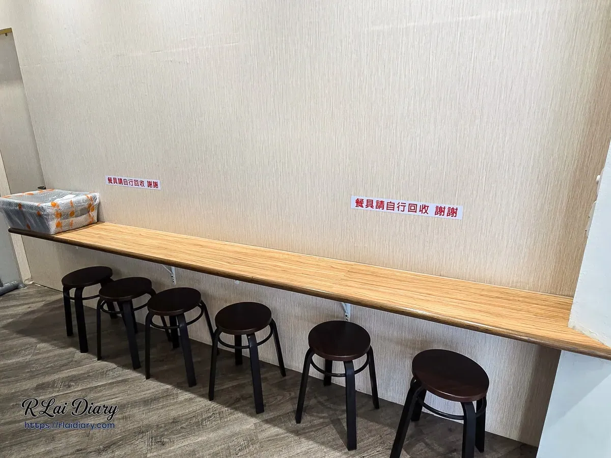 店內用餐區長吧檯與深色圓凳，營造現代簡約的用餐氛圍
