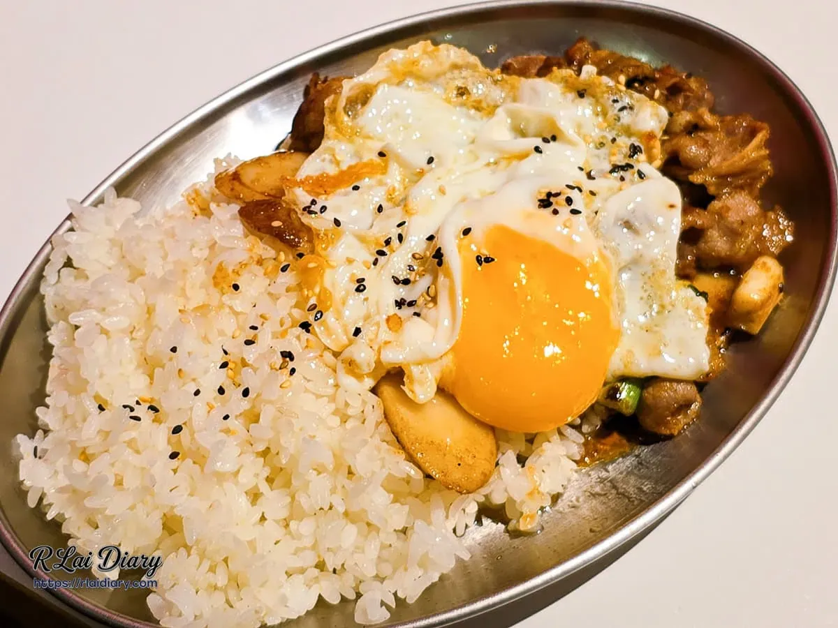 韓式烤牛肉飯淋上金黃蛋液與白米飯的誘人視覺特寫