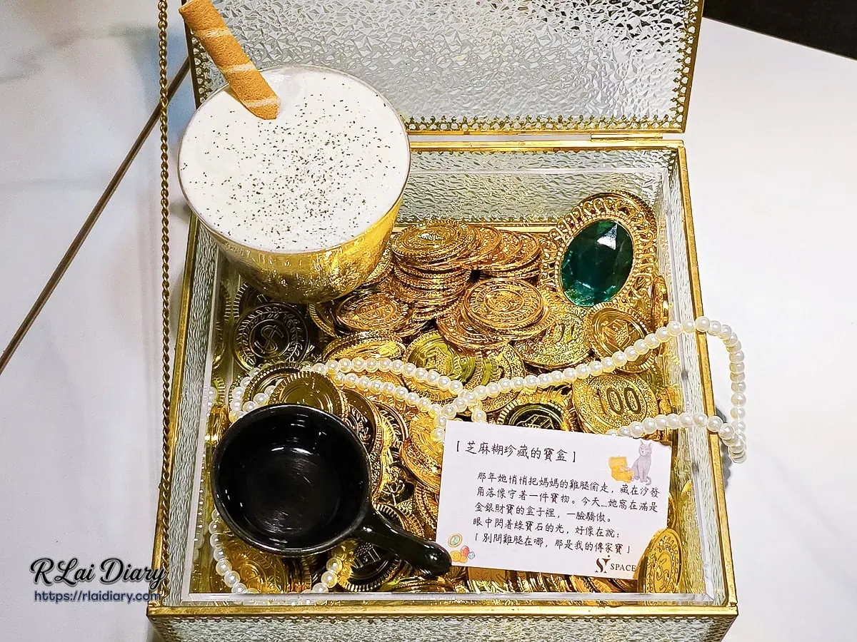 調酒「芝麻糊珍藏的寶盒」全貌，玻璃寶盒內鋪滿金幣與珠寶，極具視覺張力