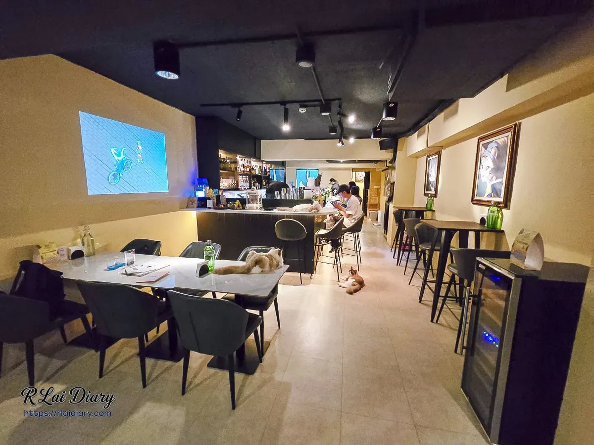貓咪餐酒館空間細節，投影幕播放輕鬆影像，牆面飾以優雅貓咪藝術肖像畫