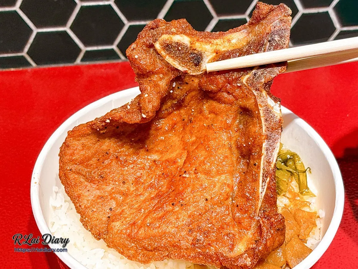 筷子夾起招牌唐山排骨，展現骨邊肉在高溫淬鍊下散發的焦香色澤與紮實質地