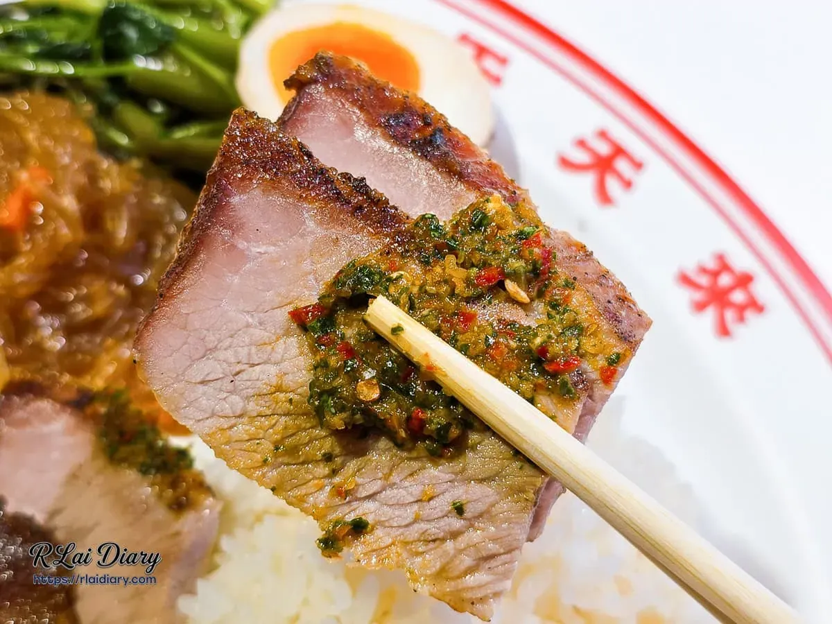 夾起帶有焦香色澤的泰式烤霜降豬肉片與特製酸辣醬料