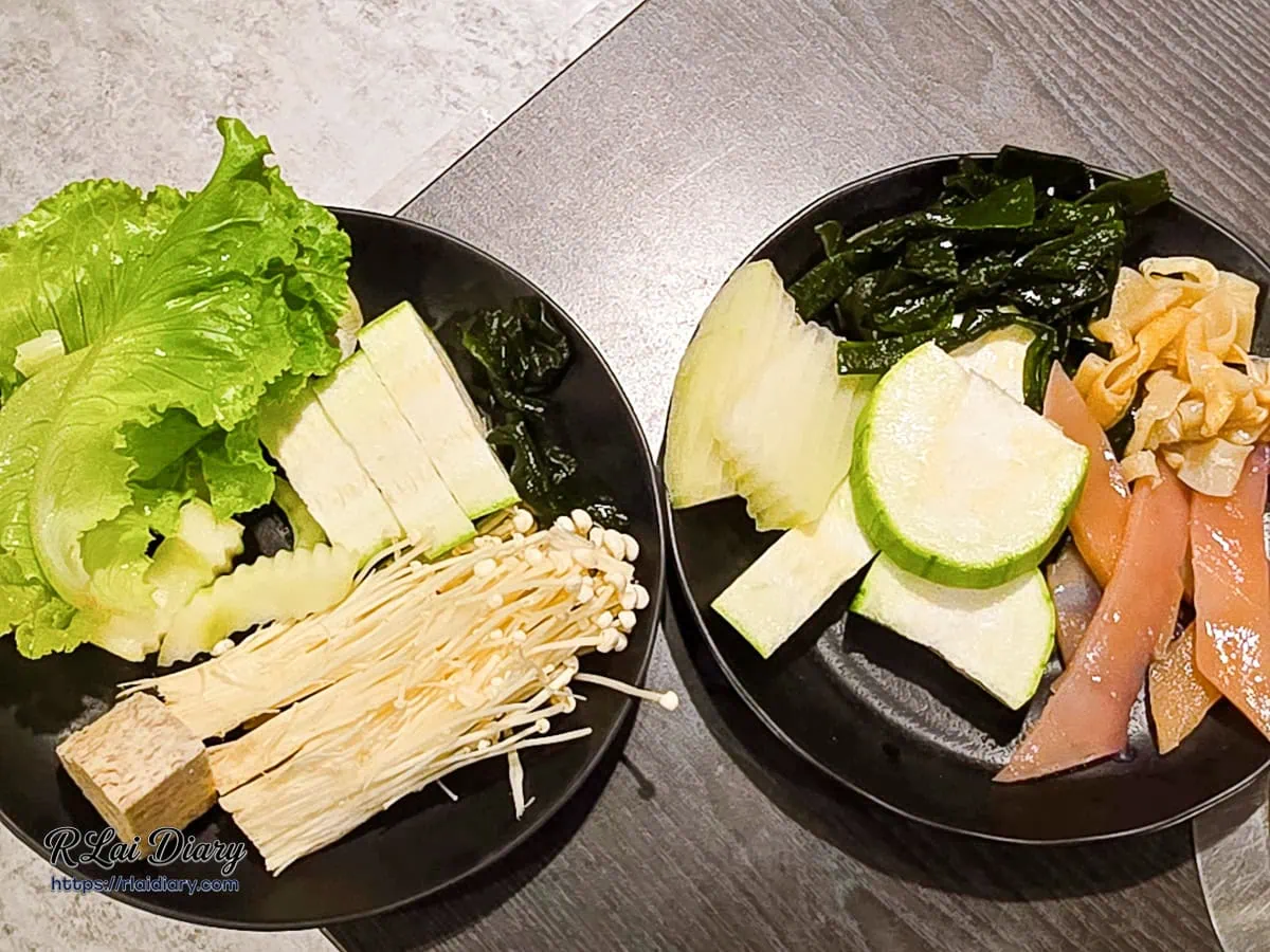 新千葉火鍋西門店餐桌上盛裝的翠綠生菜金針菇絲瓜海帶與剔透魷魚片
