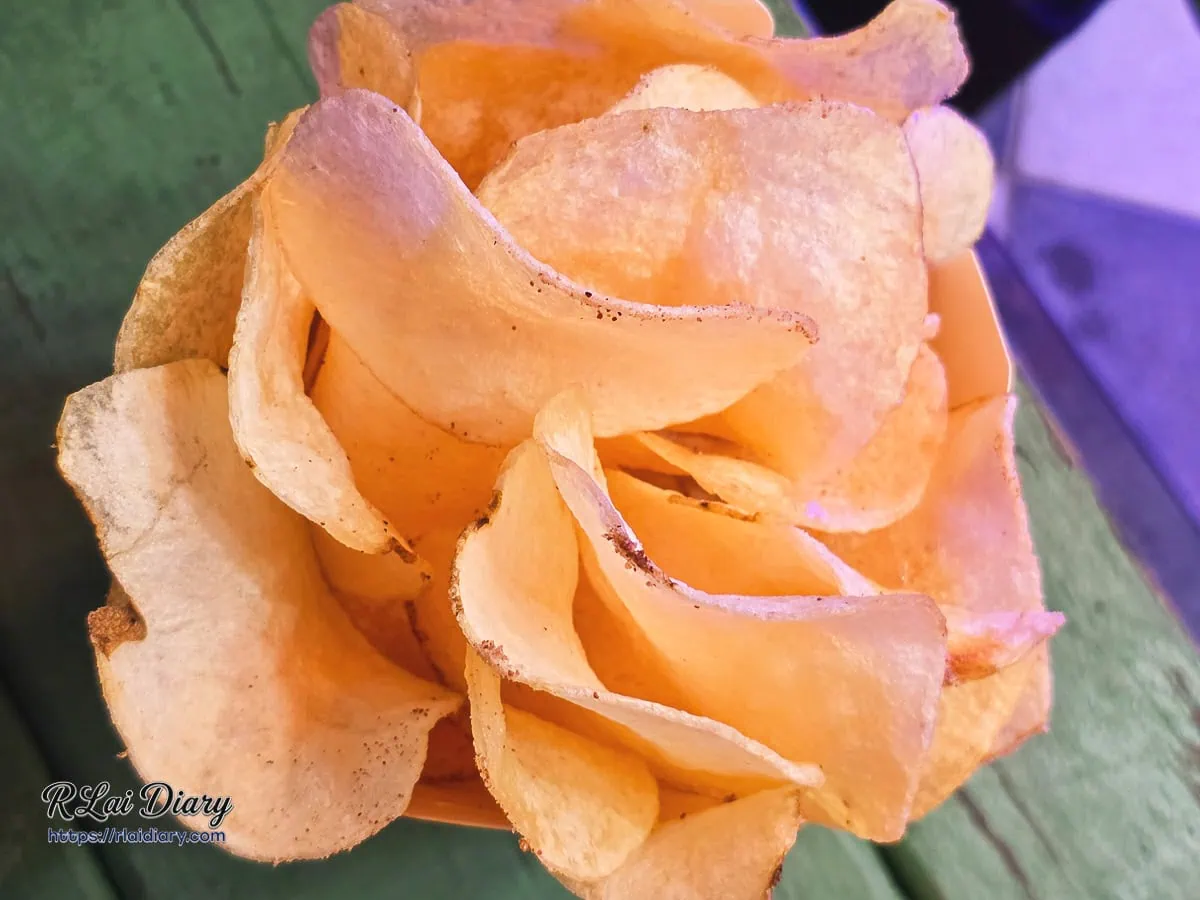 霓虹光影映照下紙盒內現點現炸薄如蟬翼的新鮮馬鈴薯洋芋片