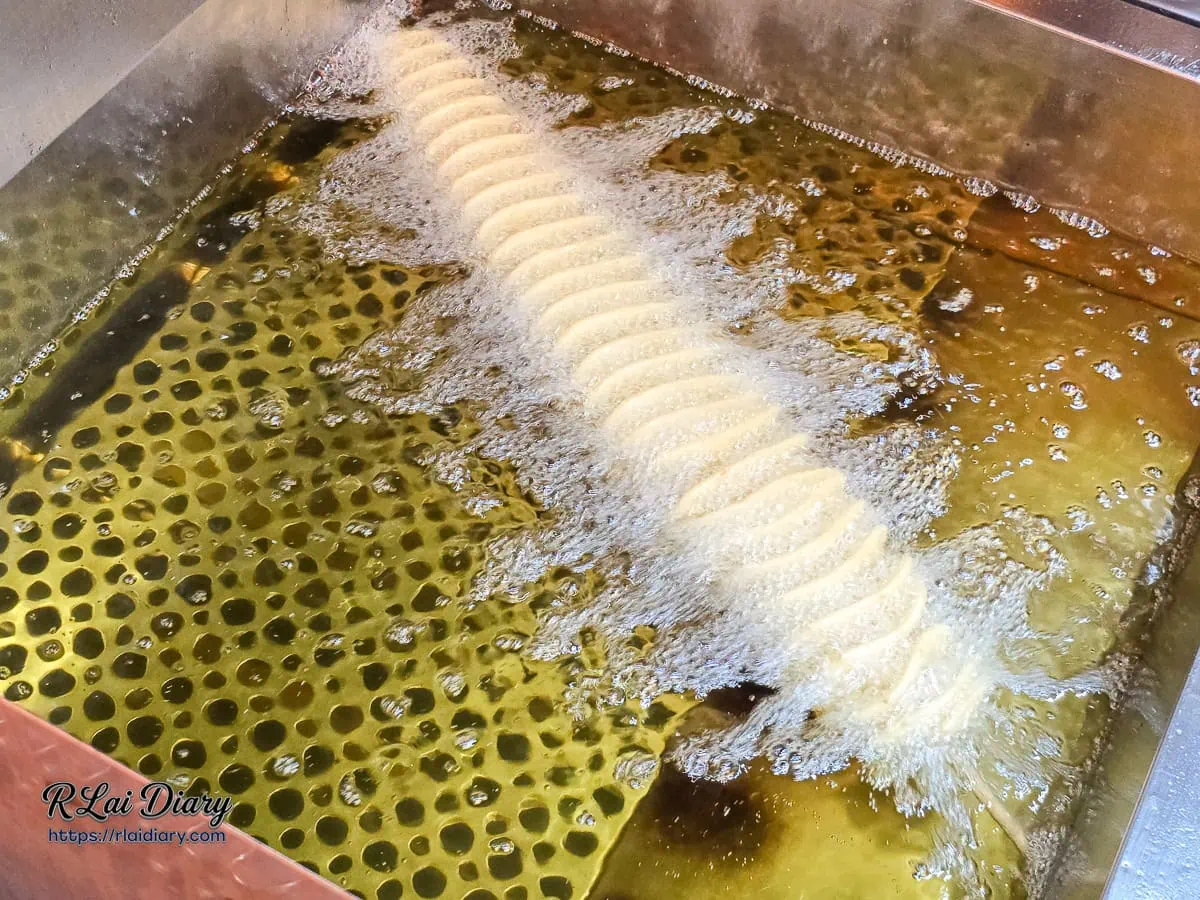 50公分旋風薯塔沉浸在清澈高溫熱油中炸至金黃酥脆的畫面