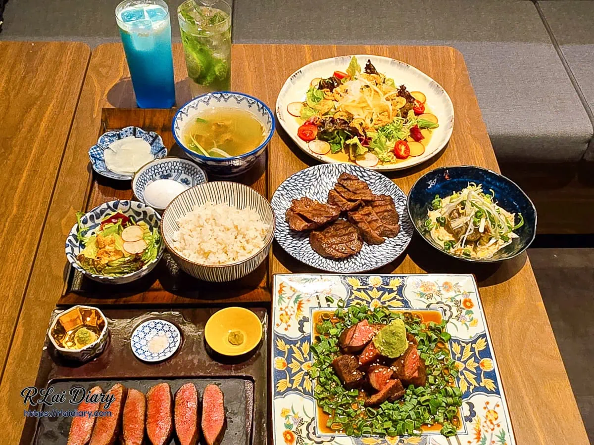 東山炭燒牛舌台北信義店滿桌菜色大合照，包含極品厚切定食、山葵牛舌與漸層氣泡飲