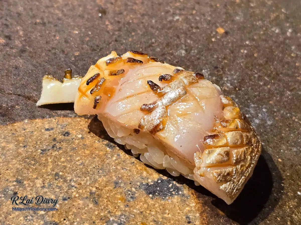 鮨処律板前藝術：太刀魚壽司特寫，網格狀細緻刀工經炭火淬鍊後的立體美感
