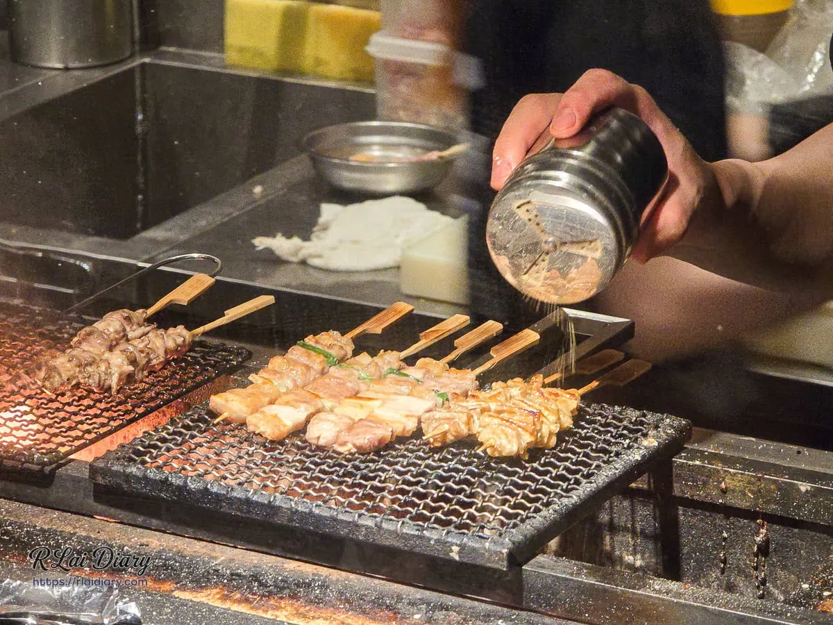 蛋串燒鹽烤居酒屋師傅手持鹽罐為炭火上的串燒精準撒鹽調味