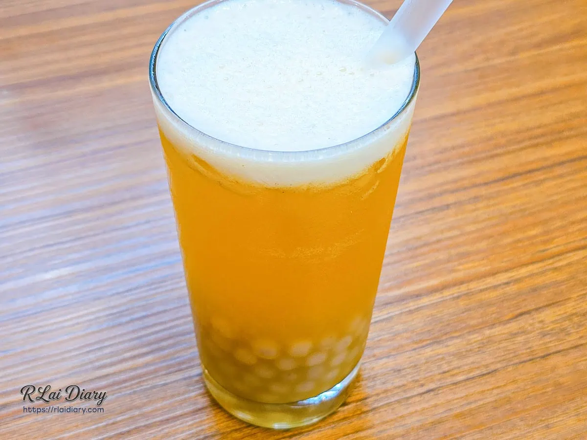 三月春百香綠茶加特製大甲芋圓，澄澈金黃茶湯頂層覆蓋著現搖綿密氣泡，完美鎖住熱帶鮮果酸香與草本尾韻