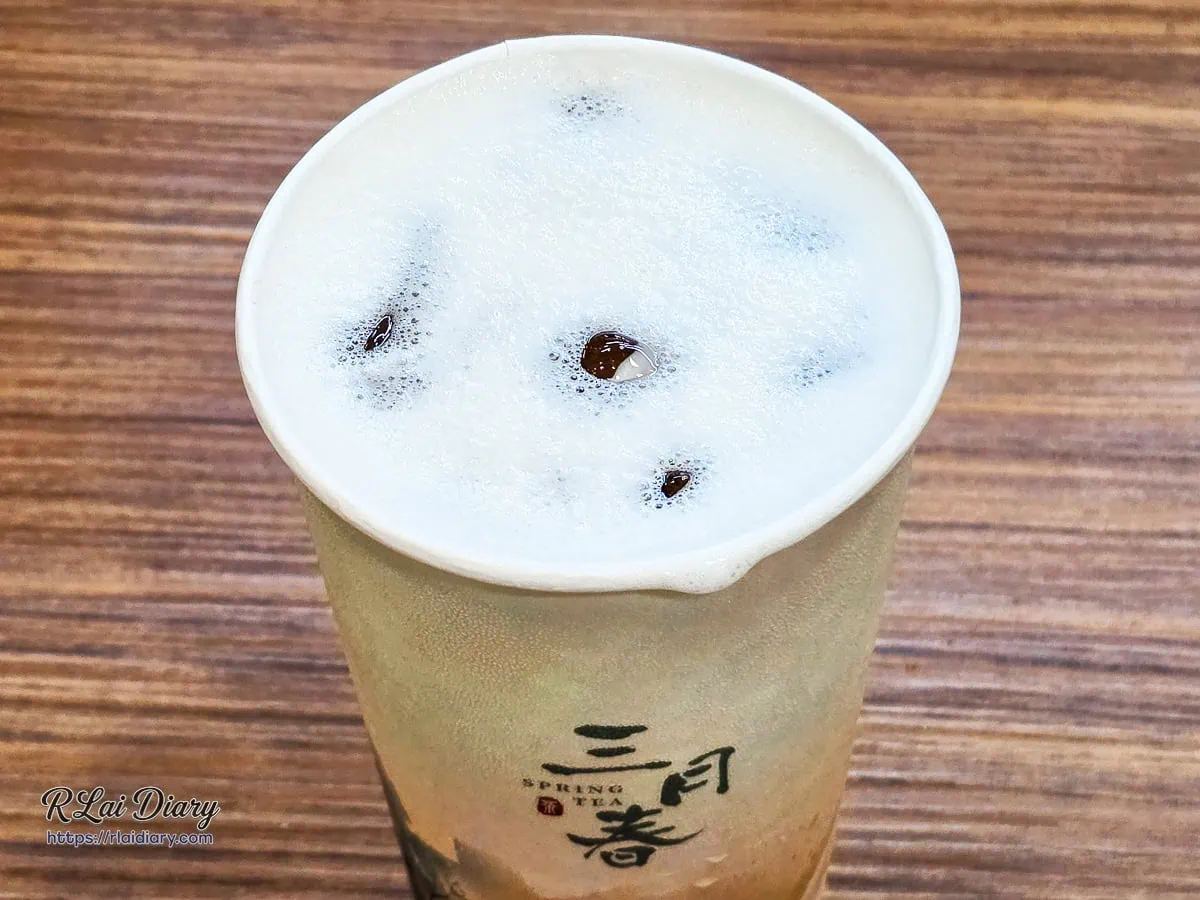 三月春招牌純茶，紙杯頂端覆蓋著宛如春日晨霧般的手搖細緻乳白浮沫，輕柔凝聚茶葉舒展釋放的乾淨日光氣息