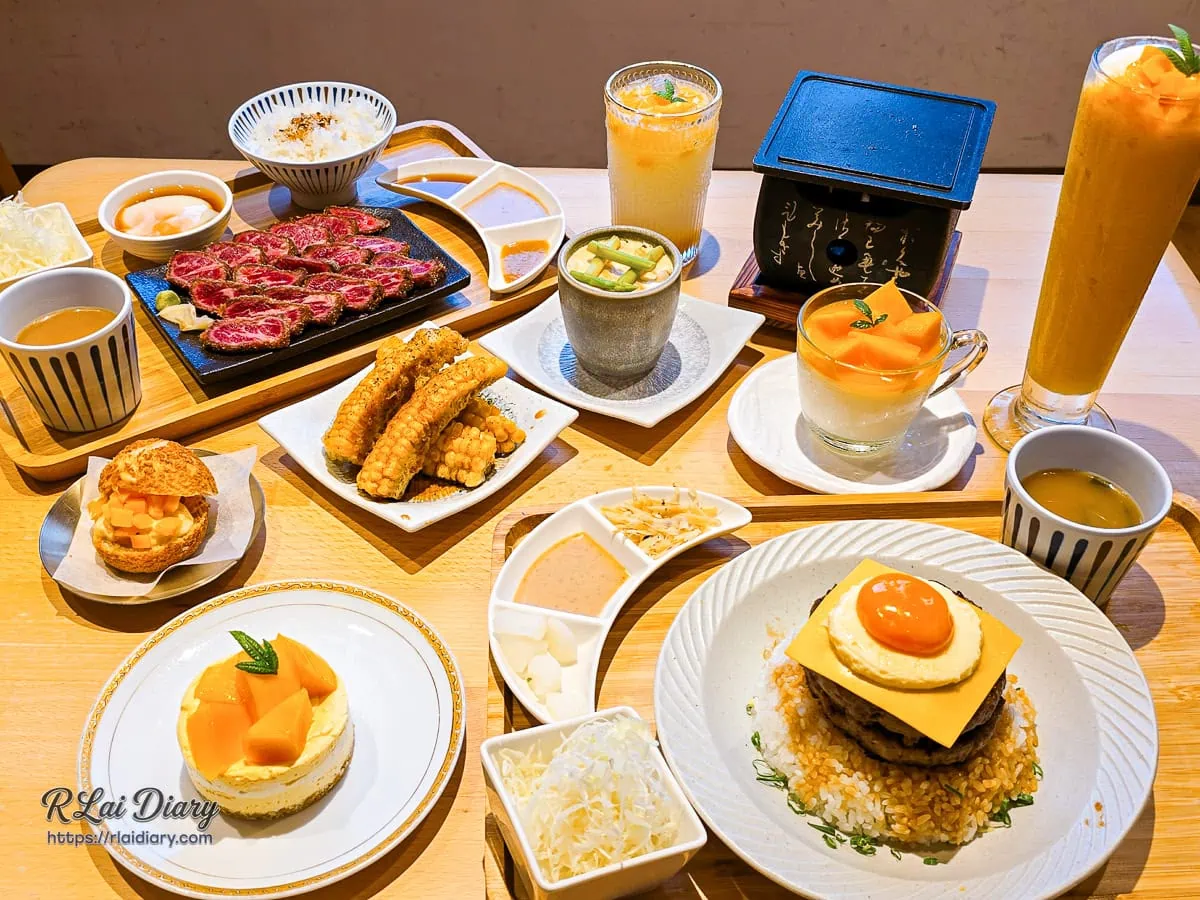 嵐山熟成牛かつ專売台中西區健行店滿桌豐盛日式餐點合照，包含招牌炸特選級翼板牛排定食、雙層漢堡排起司丼飯，以及夏季限定芒果季甜點與飲品