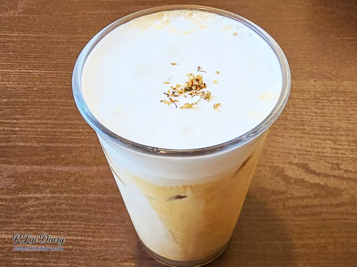 LOCC Coffee 招牌特調「桂花拿鐵」，純白綿密奶泡上大氣灑落澄黃乾燥桂花瓣