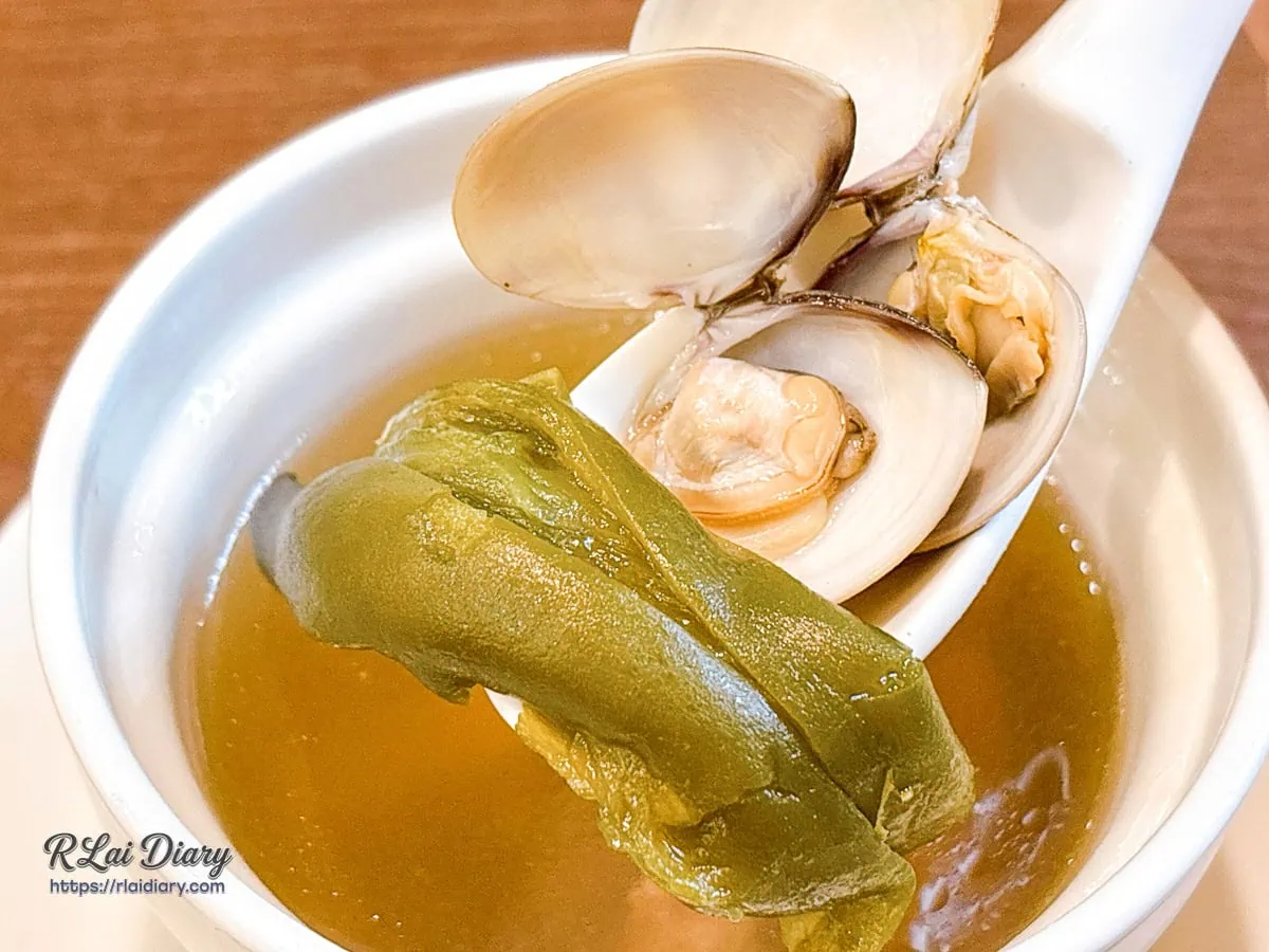 禾作私房菜「每日例湯」湯匙撈起特寫，包含大塊軟嫩雞肉、新鮮蛤蜊與剝皮辣椒