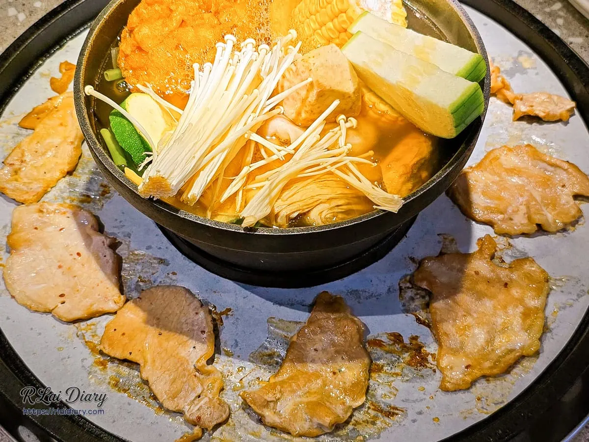 鑄鐵盤上炙烤焦脆肉片與中央翻滾的爆炒石頭鍋